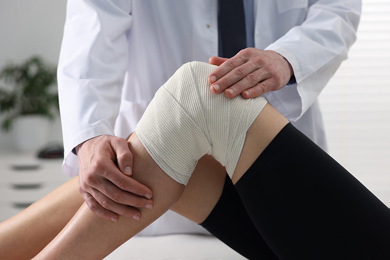 Orthopaedic specialist examining patient's knee