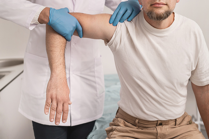 Rotator cuff specialist evaluating shoulder movement after rotator cuff surgery during a follow-up consultation