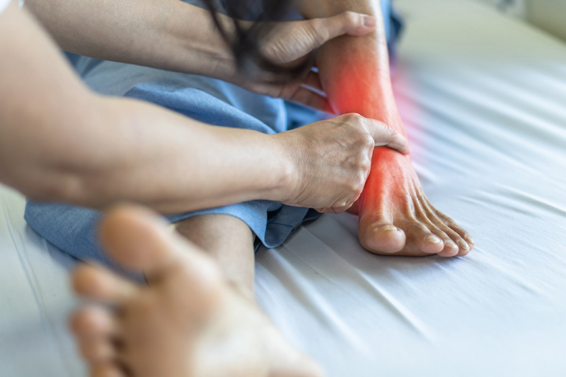 A patient having his foot examined while lying on a bed