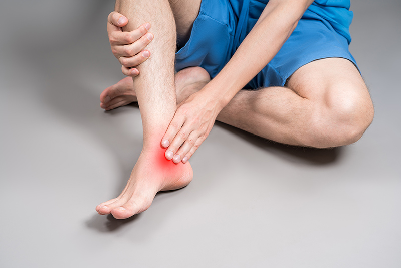 A soft red glow indicating Achilles tendon pain on a man's foot
