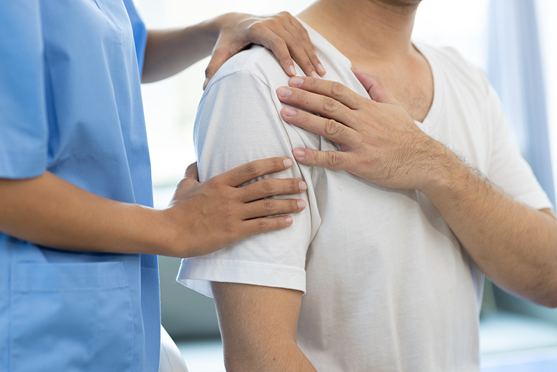 A medical professional assessing a man's shoulder
