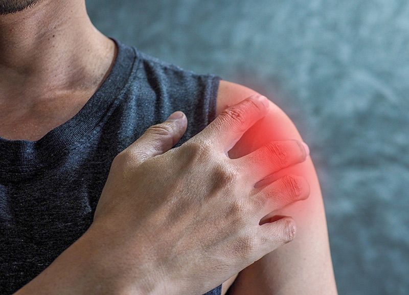 A man holding his shoulder with a soft red glow indicating shoulder pain