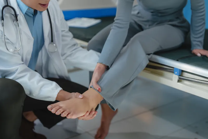 Surgeon assessing woman's ankle sprain