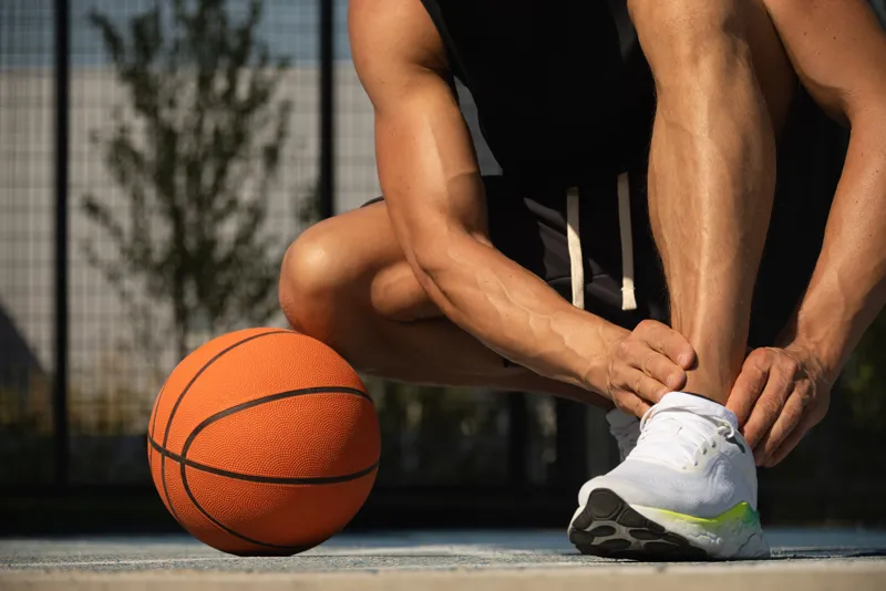 Man with basketball checking for ankle sprain