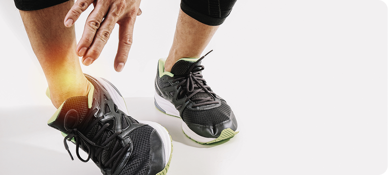 A person holding their sprained ankle, showing signs of swelling and discomfort.